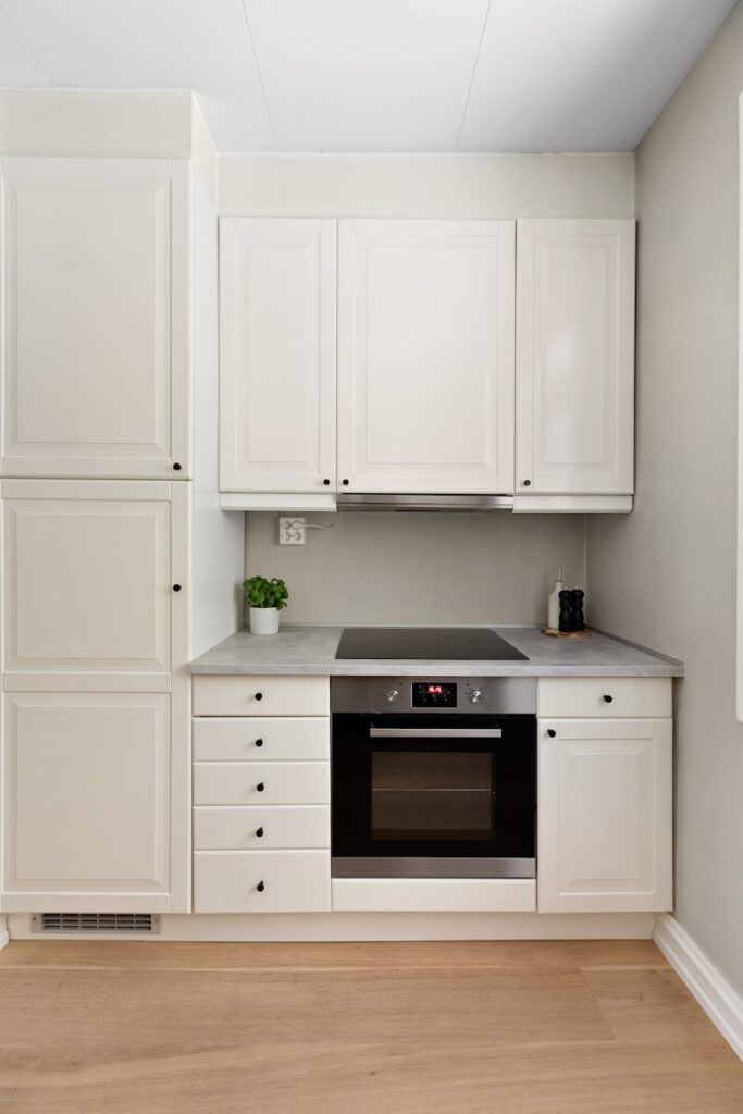 A kitchen with white cabinets and a black stove top oven